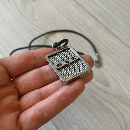 Silver pendant held in a hand with a light background