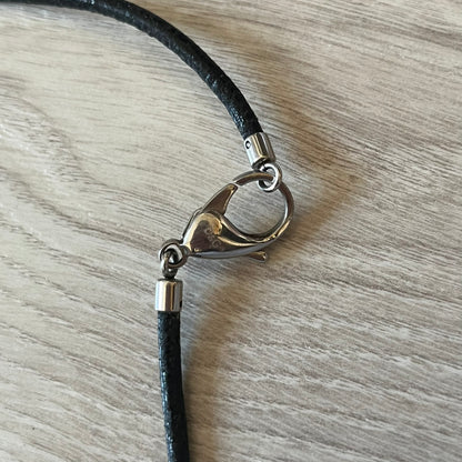 Close-up of a black cord with a silver clasp on a wooden surface