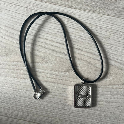 Dolce &amp; Gabbana Mesh Necklace featuring a stainless steel plate engraved with the D&amp;G logo, attached to a black leather cord. The reverse side displays a detailed grid-style mesh design. Model DJ0452, crafted with precision and industrial-inspired elegance.