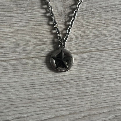 Dolce & Gabbana AW2009 Military Star Dog Tag Necklace in grey. Features a 3D black star mounted on a silver-tone metal circle with an engraved D&G logo at the bottom, suspended from a silver cable chain. Comes complete with original box and tags.