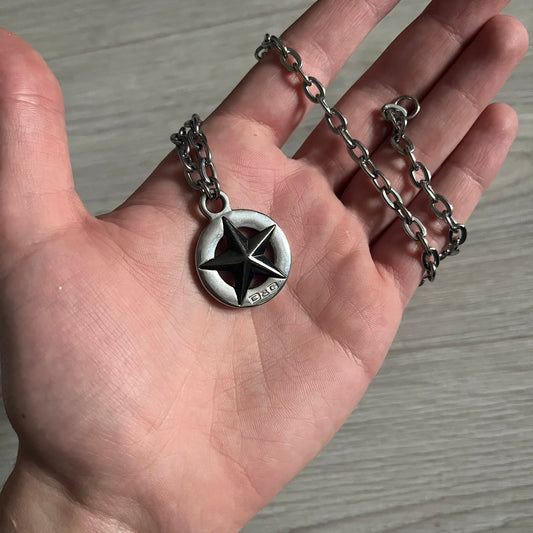 Dolce & Gabbana AW2009 Military Star Dog Tag Necklace in grey. Features a 3D black star mounted on a silver-tone metal circle with an engraved D&G logo at the bottom, suspended from a silver cable chain. Comes complete with original box and tags.