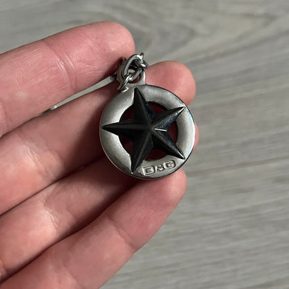 Dolce & Gabbana AW2009 Military Star Dog Tag Necklace in grey. Features a 3D black star mounted on a silver-tone metal circle with an engraved D&G logo at the bottom, suspended from a silver cable chain. Comes complete with original box and tags.