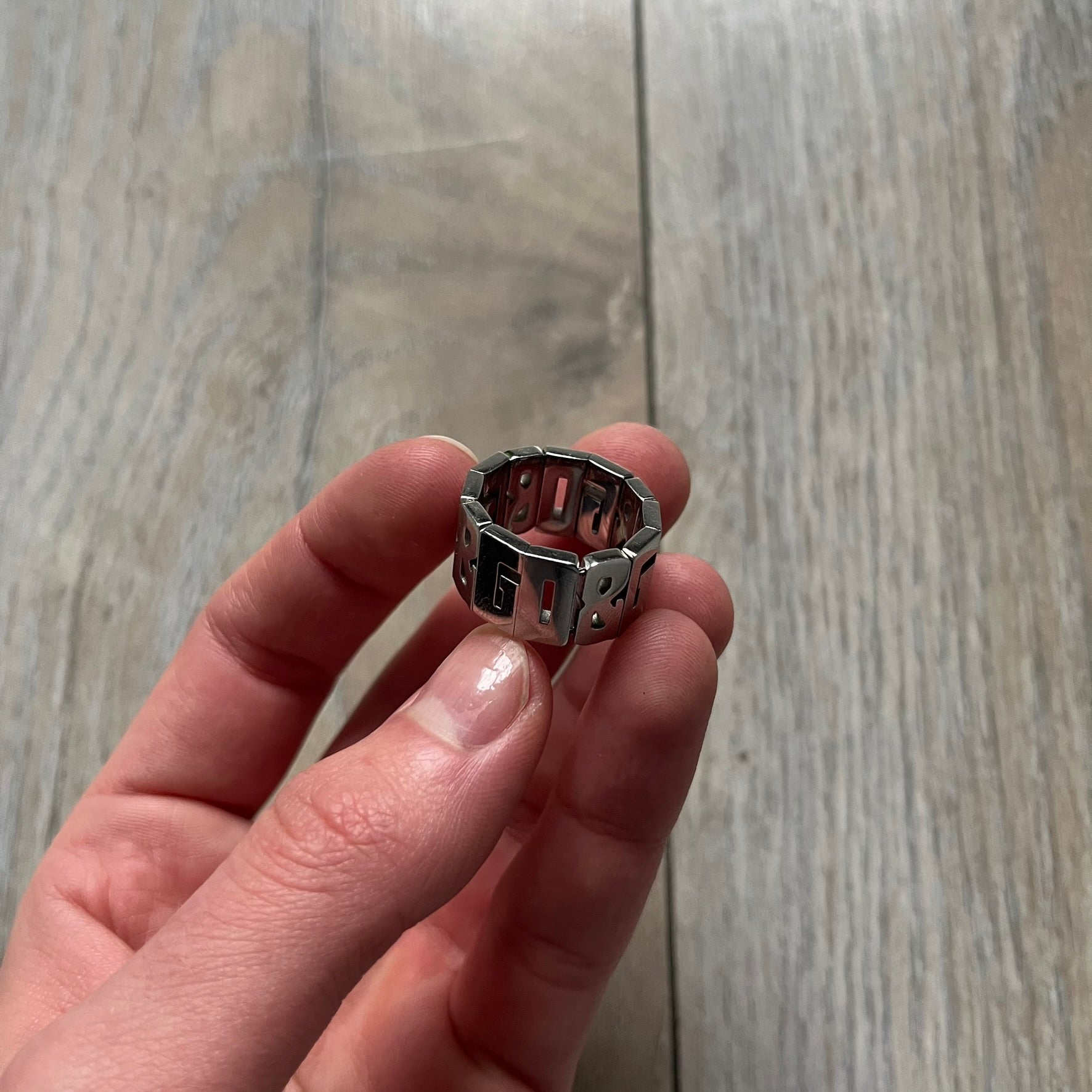 Dolce & Gabbana Overlap DJ0538 Ring is a stainless steel ring constructed entirely from cutout D&G letters. The design features 12 letters forming 4 repeating D&G sets, with each letter’s inner spaces incorporated into the openwork structure