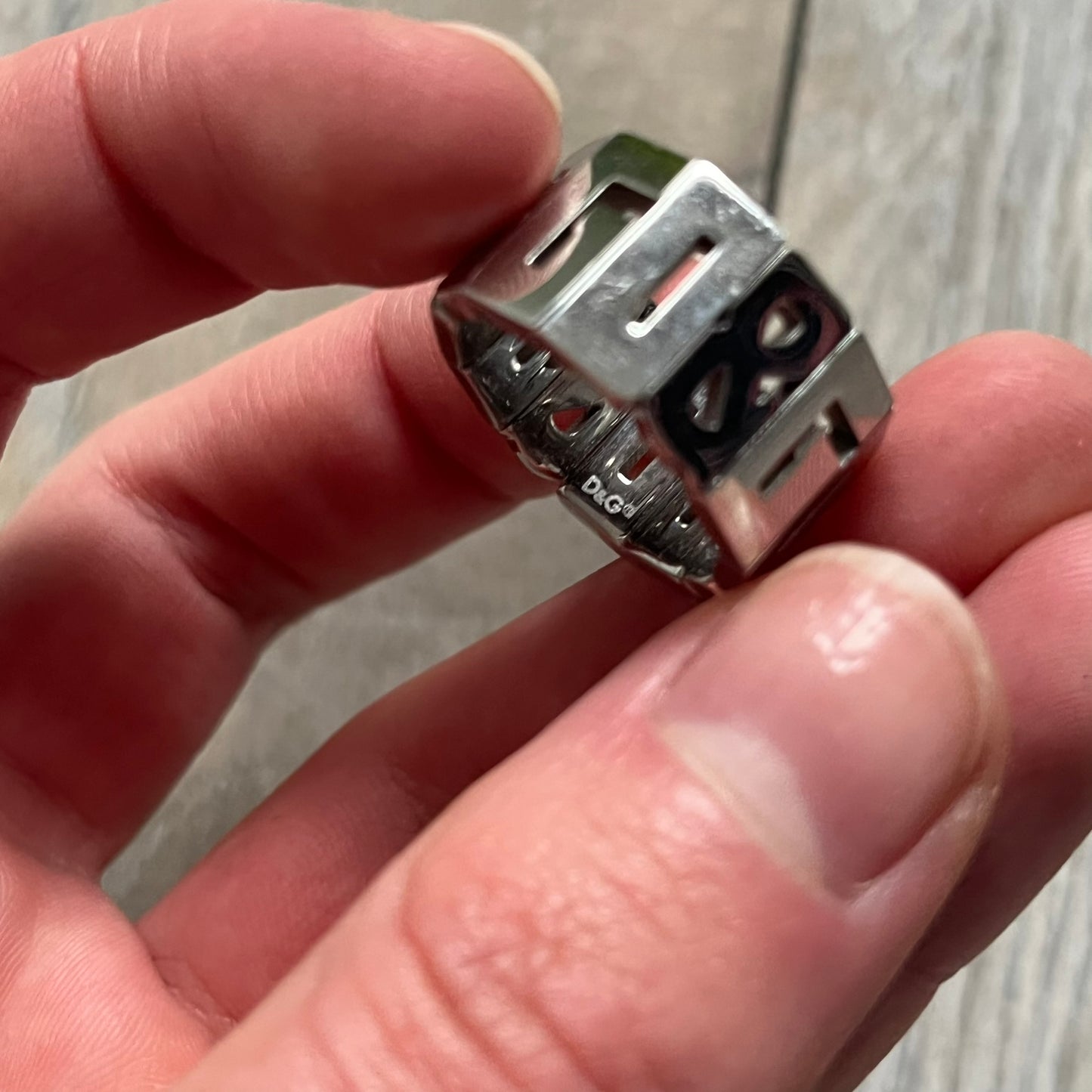 Dolce & Gabbana Overlap DJ0538 Ring is a stainless steel ring constructed entirely from cutout D&G letters. The design features 12 letters forming 4 repeating D&G sets, with each letter’s inner spaces incorporated into the openwork structure