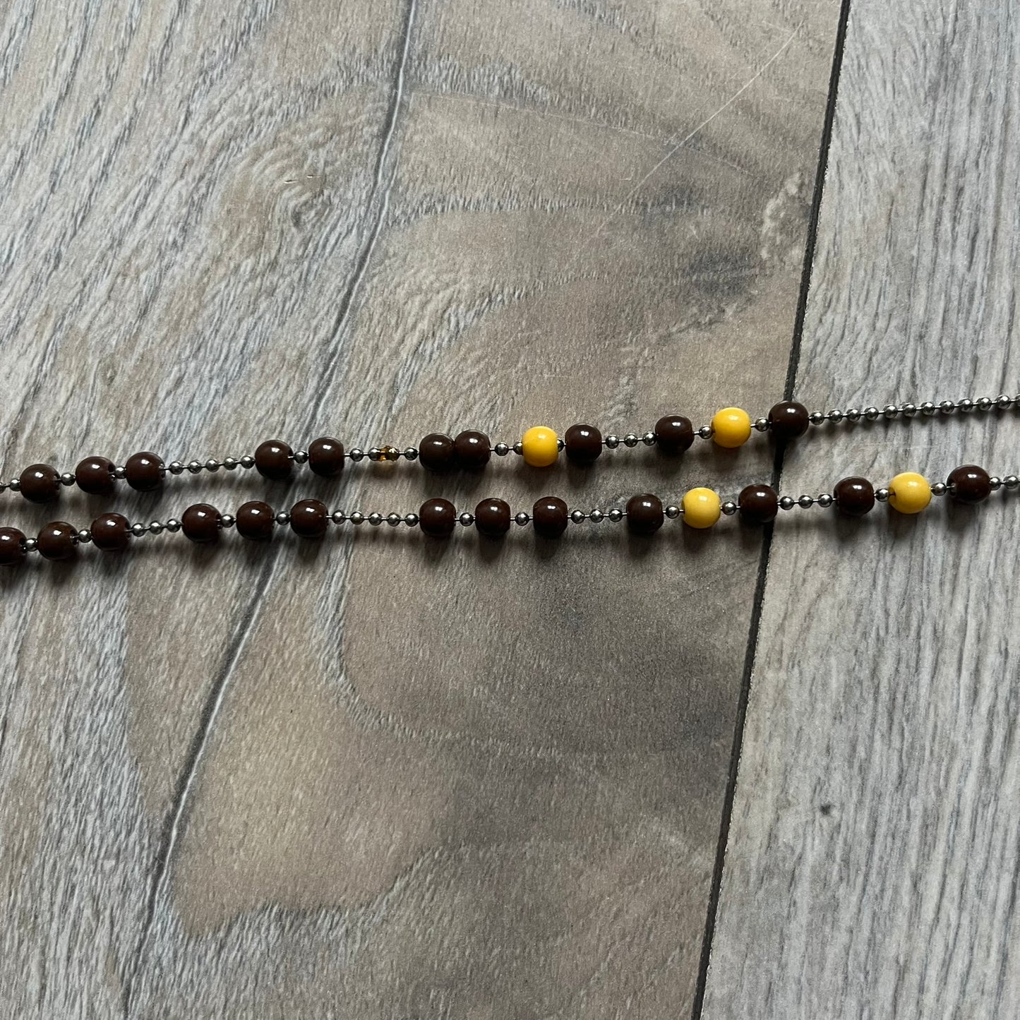 Dolce &amp; Gabbana Pearl Brown Rosary Necklace from the 2000s era. The necklace features a silver-tone metal cross with a D&amp;G logo, connected via a black leather link to a metal chain with alternating brown and yellow pearl-style beads. Rosary-style construction with mixed materials including metal, leather, and resin pearls. Comes complete with the big dustbag.