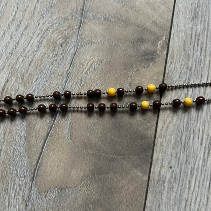 Dolce &amp; Gabbana Pearl Brown Rosary Necklace from the 2000s era. The necklace features a silver-tone metal cross with a D&amp;G logo, connected via a black leather link to a metal chain with alternating brown and yellow pearl-style beads. Rosary-style construction with mixed materials including metal, leather, and resin pearls. Comes complete with the big dustbag.