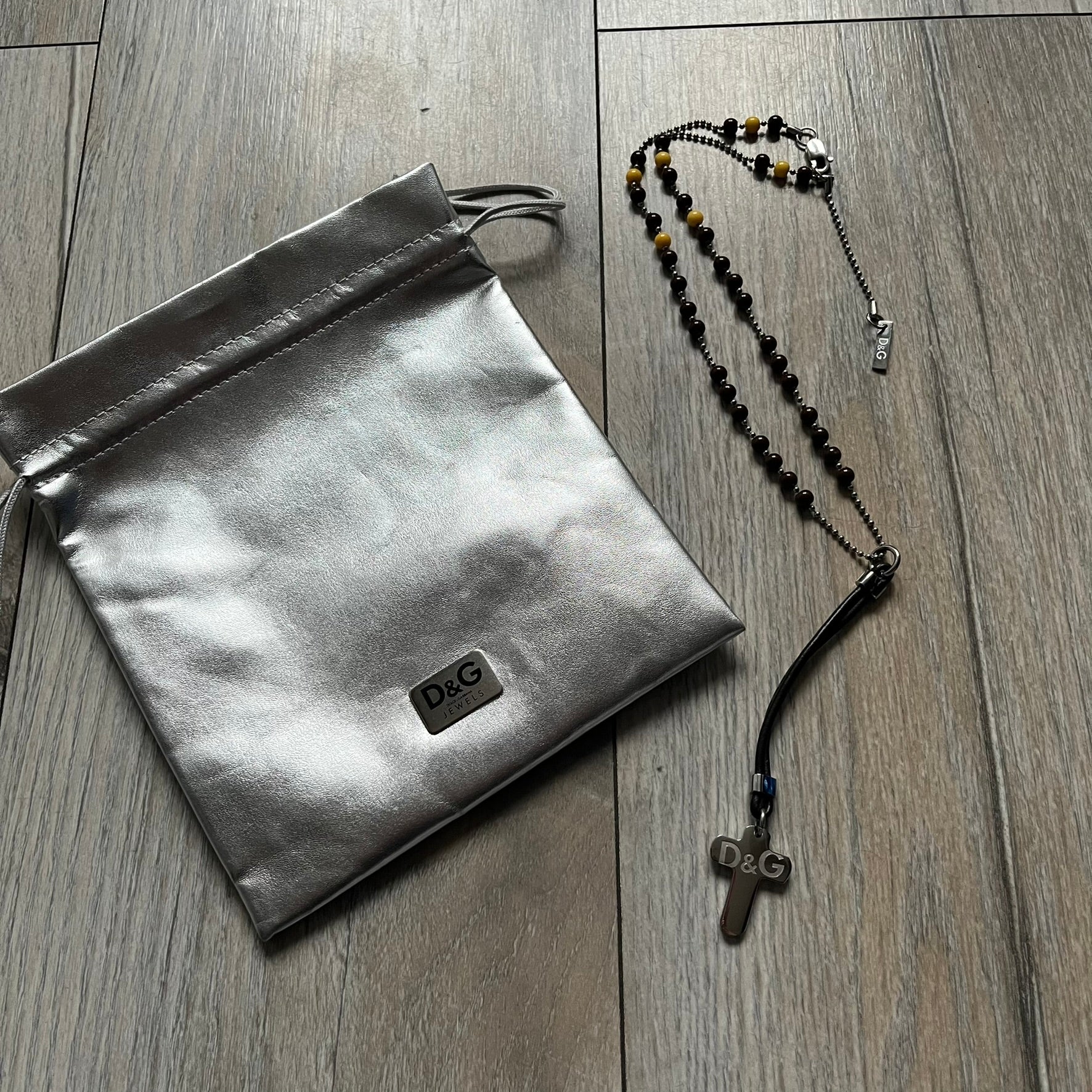Dolce &amp; Gabbana Pearl Brown Rosary Necklace from the 2000s era. The necklace features a silver-tone metal cross with a D&amp;G logo, connected via a black leather link to a metal chain with alternating brown and yellow pearl-style beads. Rosary-style construction with mixed materials including metal, leather, and resin pearls. Comes complete with the big dustbag.