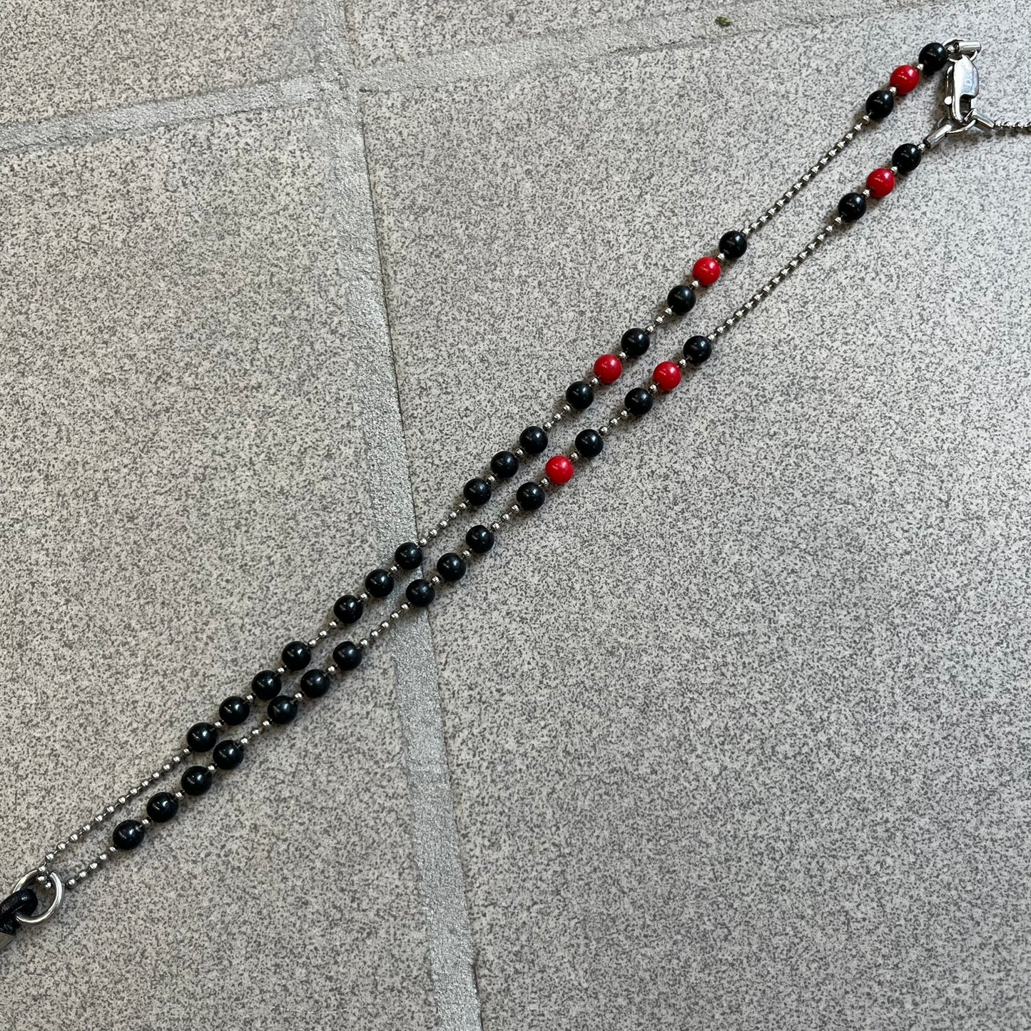 Dolce &amp; Gabbana Pearl Red/Black Rosary Necklace from the 2000's era. The necklace features a silver-tone metal cross with a D&amp;G logo, connected via a black leather link to a metal chain with alternating red and black pearl-style beads. Rosary-style construction with mixed materials including metal, leather, and resin pearls.&nbsp;