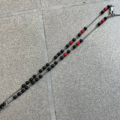 Dolce &amp; Gabbana Pearl Red/Black Rosary Necklace from the 2000's era. The necklace features a silver-tone metal cross with a D&amp;G logo, connected via a black leather link to a metal chain with alternating red and black pearl-style beads. Rosary-style construction with mixed materials including metal, leather, and resin pearls.&nbsp;