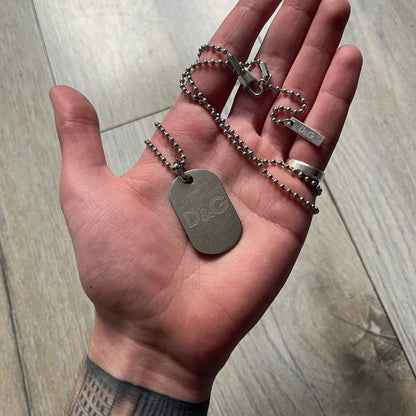Dolce &amp; Gabbana plain logo dog tag necklace in silver-tone stainless steel, featuring the iconic D&amp;G logo engraved on a sleek tag. Suspended on a classic ball chain with a regulated size. A versatile accessory that combines minimal branding with everyday wearability.