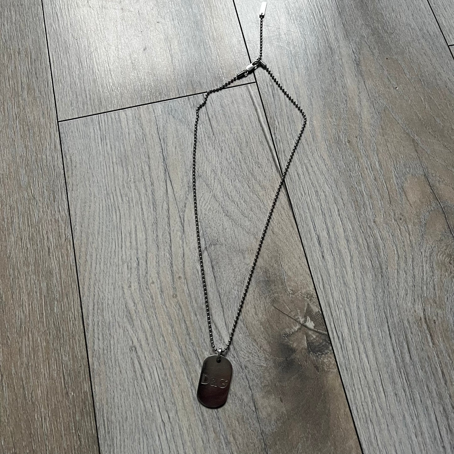 Dolce &amp; Gabbana plain logo dog tag necklace in silver-tone stainless steel, featuring the iconic D&amp;G logo engraved on a sleek tag. Suspended on a classic ball chain with a regulated size. A versatile accessory that combines minimal branding with everyday wearability.