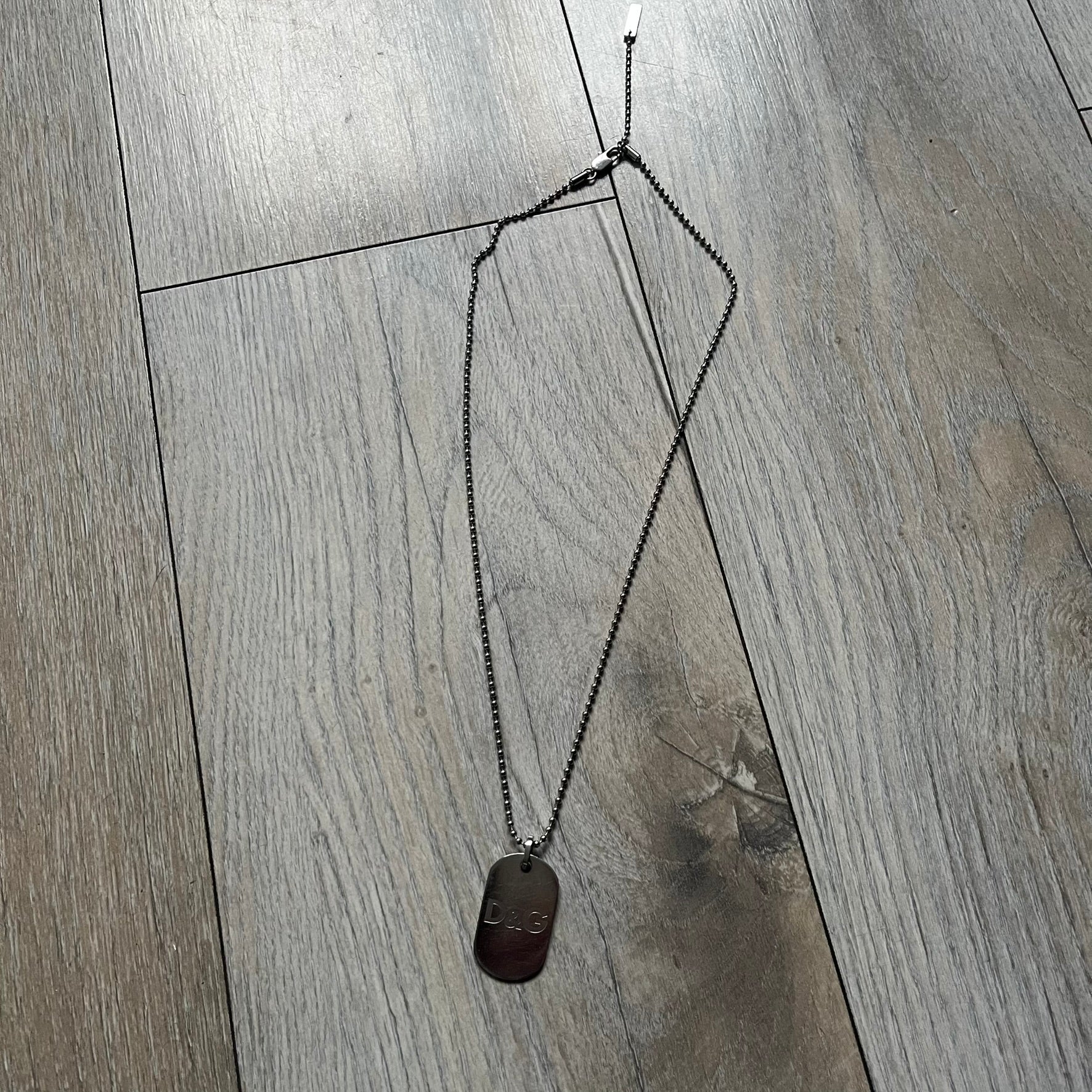 Dolce &amp; Gabbana plain logo dog tag necklace in silver-tone stainless steel, featuring the iconic D&amp;G logo engraved on a sleek tag. Suspended on a classic ball chain with a regulated size. A versatile accessory that combines minimal branding with everyday wearability.