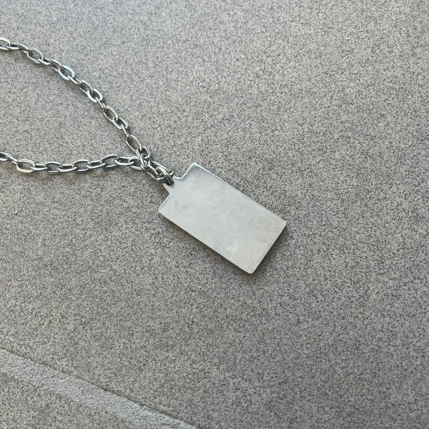 Dolce &amp; Gabbana Propaganda Dog Tag Necklace, featuring a silver stainless steel square tag with four visible screws and the D&amp;G logo engraved on the front. The tag hangs from a durable cable chain, combining sturdy construction with clean, industrial-inspired detailing.