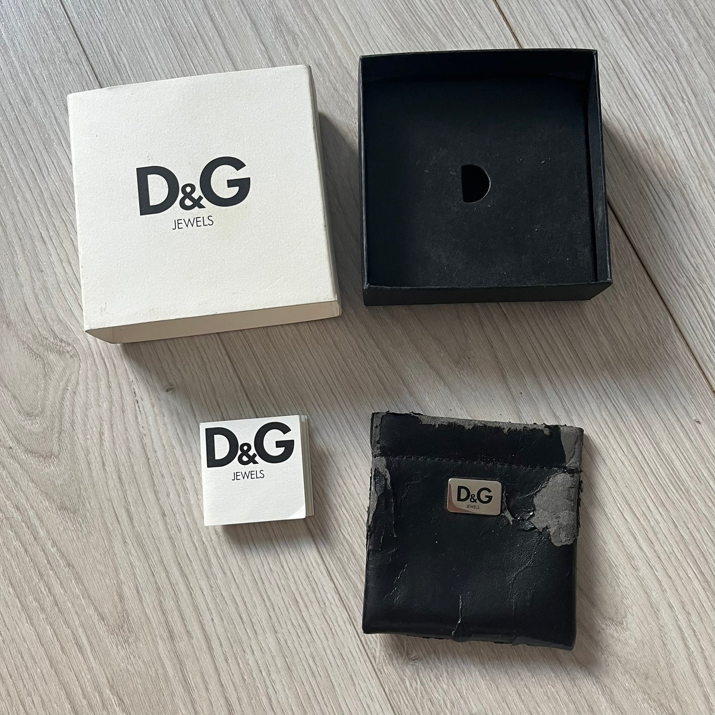 D&G Jewels packaging including a white box, black box, and jewelry pouch on a wooden surface.