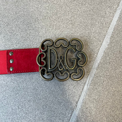 Dolce &amp; Gabbana Red Elastic Hearts Belt is made from red elastic material. The buckle is a metal D&amp;G logo surrounded by eight heart shapes pointing outward, all finished in a dark, aged-looking metal tone. The belt comes with the original hologram tag attached.