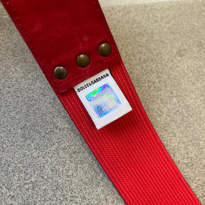 Dolce &amp; Gabbana Red Elastic Hearts Belt is made from red elastic material. The buckle is a metal D&amp;G logo surrounded by eight heart shapes pointing outward, all finished in a dark, aged-looking metal tone. The belt comes with the original hologram tag attached.