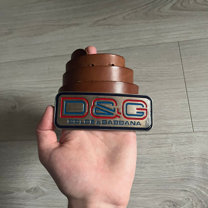 Dolce &amp; Gabbana Red &amp; Blue Leather Belt featuring a rectangular silver-tone buckle with a navy border. The buckle displays a large D&amp;G logo in blue with a red outline and “Dolce &amp; Gabbana” text in blue beneath. Finished with a brown leather strap.