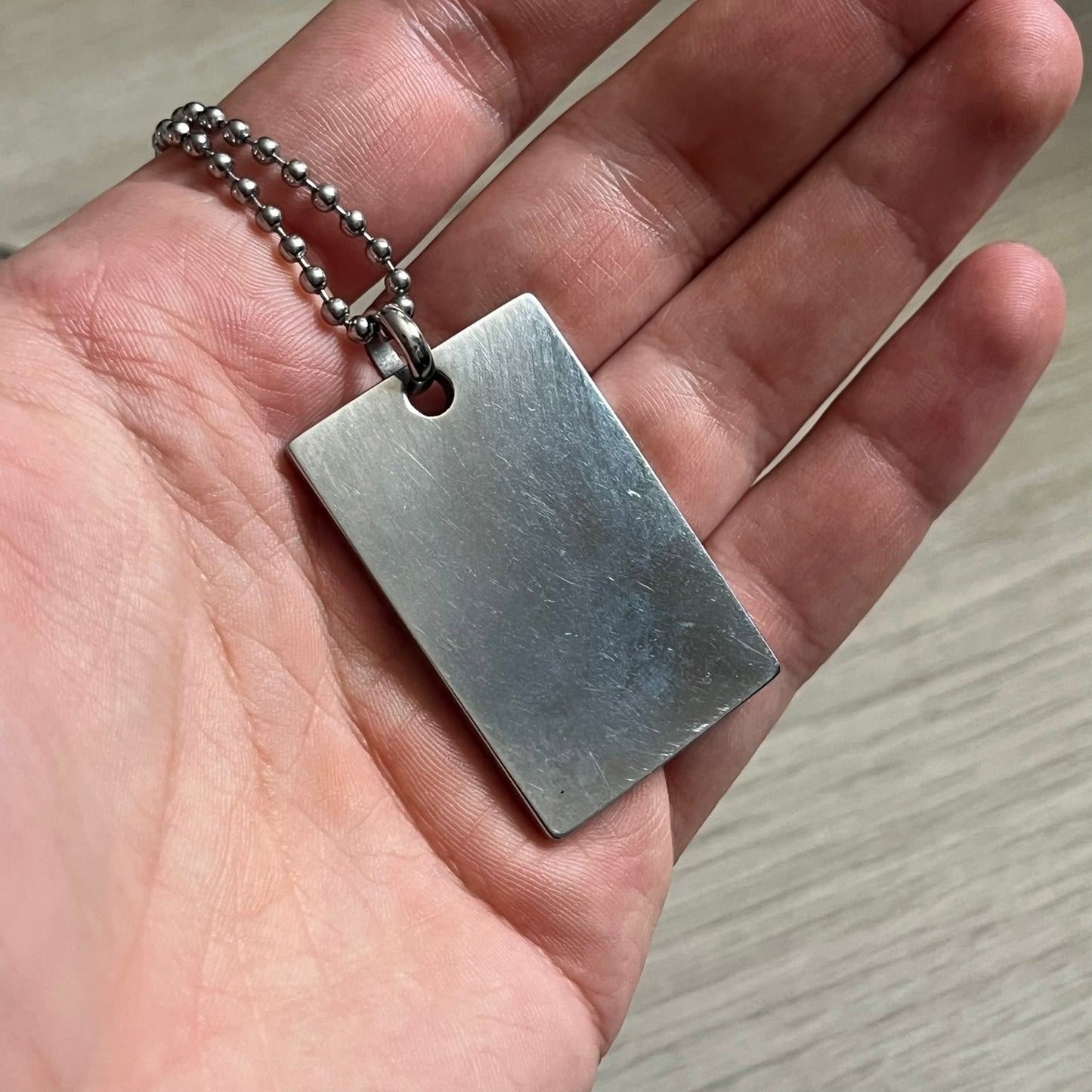 Dolce & Gabbana Rhinestones Dog Tag Necklace DJ0704 crafted from polished stainless steel. Features a rectangular pendant with the iconic D&G logo detailed in rhinestones, and “Dolce & Gabbana” engraved subtly below. Secured with a lobster clasp and finished with a durable ball chain.