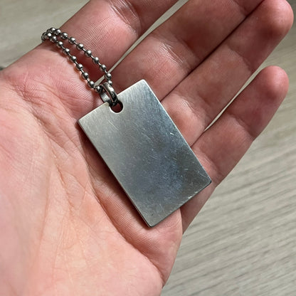 Dolce & Gabbana Rhinestones Dog Tag Necklace DJ0704 crafted from polished stainless steel. Features a rectangular pendant with the iconic D&G logo detailed in rhinestones, and “Dolce & Gabbana” engraved subtly below. Secured with a lobster clasp and finished with a durable ball chain.