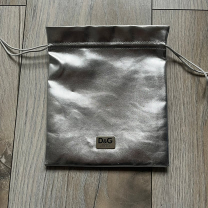 The Dolce &amp; Gabbana Room 13 Carabiner Necklace (DJ0613) is a large, heavy silver-tone necklace featuring a thick paperclip chain with oversized links. At the end of the chain is a large lobster clasp engraved with D&amp;G markings, connected to a branded carabiner. Hanging from the carabiner are two different keys with small D&amp;G logos and a black key identifier with a silver-tone plate engraved with “D&amp;G Dolce &amp; Gabbana Room 13.” The necklace comes with a large silver Dolce &amp; Gabbana dus