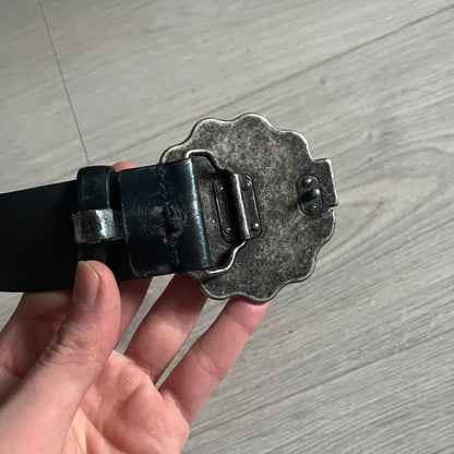 Dolce &amp; Gabbana Round Stamp Belt with a circular, wavy-edged buckle in a metallic finish. The buckle features a beige center with a bold black D&amp;G logo and “Dolce &amp; Gabbana” text beneath. Belt strap is glittery metallic blue with a black inner lining.