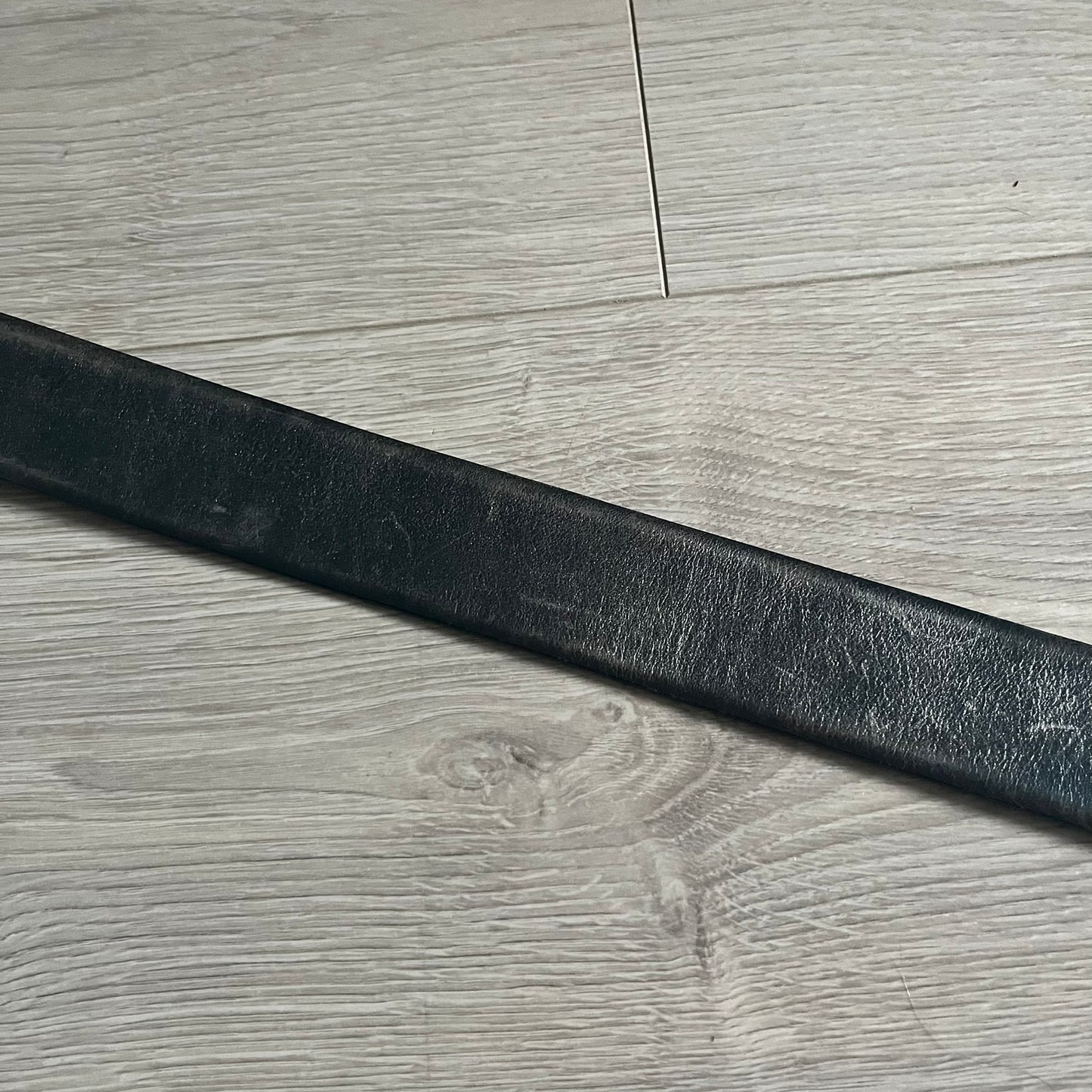 Dolce &amp; Gabbana Round Stamp Belt with a circular, wavy-edged buckle in a metallic finish. The buckle features a beige center with a bold black D&amp;G logo and “Dolce &amp; Gabbana” text beneath. Belt strap is glittery metallic blue with a black inner lining.