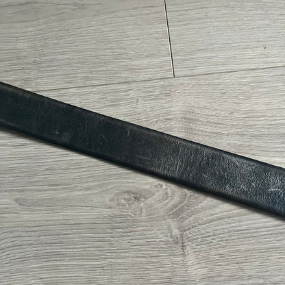 Dolce &amp; Gabbana Round Stamp Belt with a circular, wavy-edged buckle in a metallic finish. The buckle features a beige center with a bold black D&amp;G logo and “Dolce &amp; Gabbana” text beneath. Belt strap is glittery metallic blue with a black inner lining.