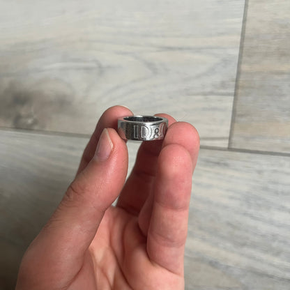 Dolce &amp; Gabbana SS04 SEX Ring is a stainless steel ring from the Spring/Summer 2004 collection. The exterior features an engraved D&amp;G logo on one side and “SEX” engraved on the opposite side. The interior is marked with a small D&amp;G logo. It has a thick band construction and polished finish.