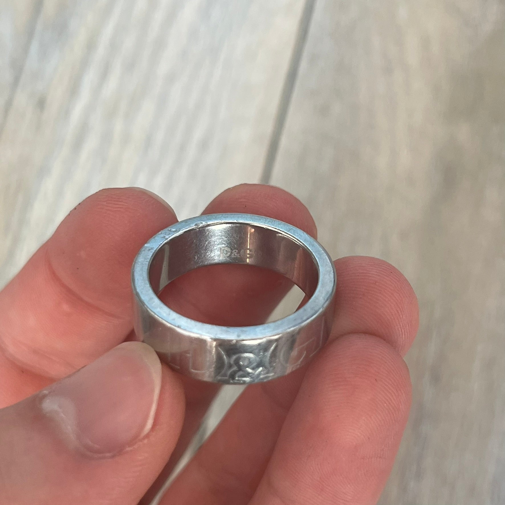 Dolce &amp; Gabbana SS04 SEX Ring is a stainless steel ring from the Spring/Summer 2004 collection. The exterior features an engraved D&amp;G logo on one side and “SEX” engraved on the opposite side. The interior is marked with a small D&amp;G logo. It has a thick band construction and polished finish.