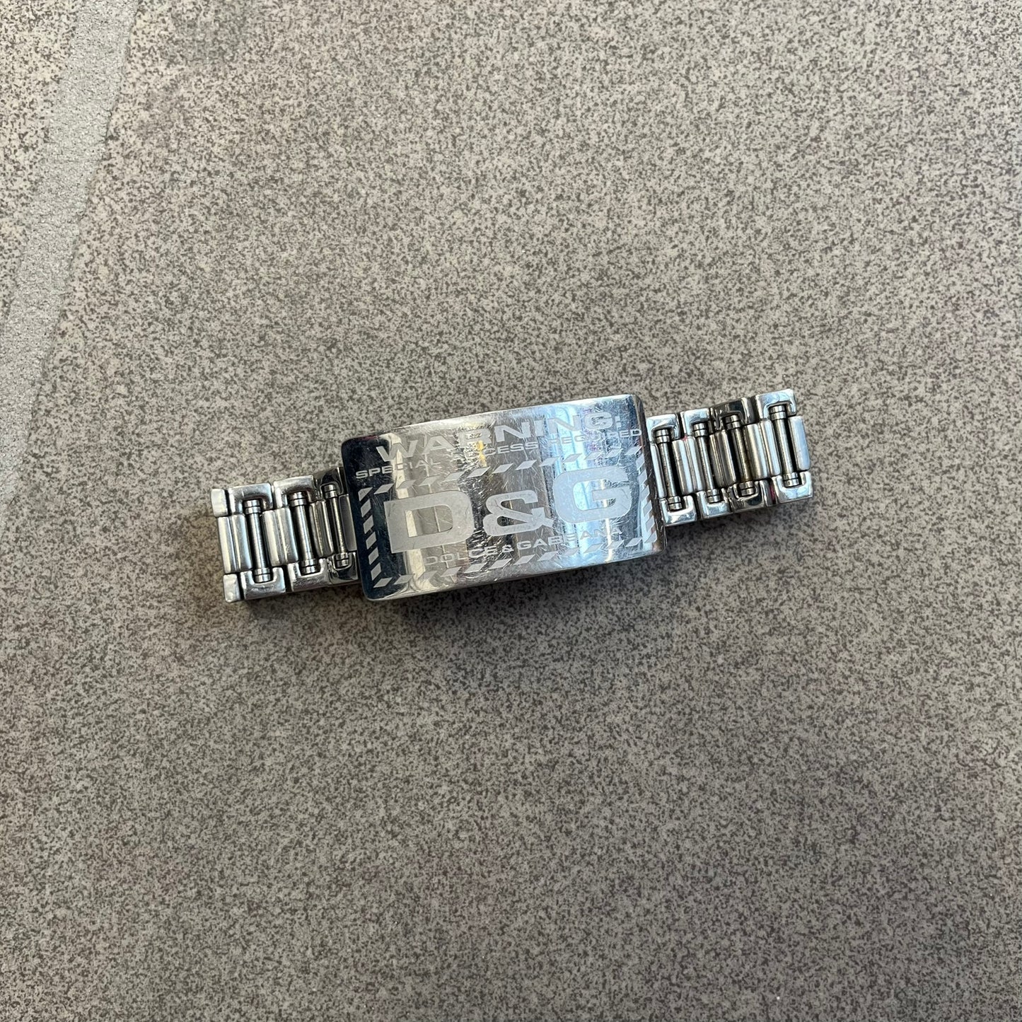 Dolce &amp; Gabbana Warning Stainless Steel Bracelet. From the Spring/Summer 2006 collection, this bracelet features a polished stainless steel design with a clip closure. The front plate displays “Warning Special Access Required” alongside D&amp;G Dolce &amp; Gabbana branding.