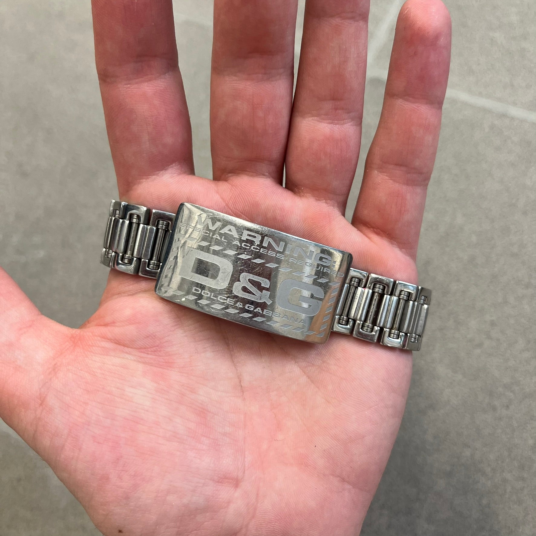 Dolce &amp; Gabbana Warning Stainless Steel Bracelet. From the Spring/Summer 2006 collection, this bracelet features a polished stainless steel design with a clip closure. The front plate displays “Warning Special Access Required” alongside D&amp;G Dolce &amp; Gabbana branding.