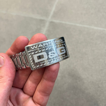 Dolce &amp; Gabbana Warning Stainless Steel Bracelet. From the Spring/Summer 2006 collection, this bracelet features a polished stainless steel design with a clip closure. The front plate displays “Warning Special Access Required” alongside D&amp;G Dolce &amp; Gabbana branding.