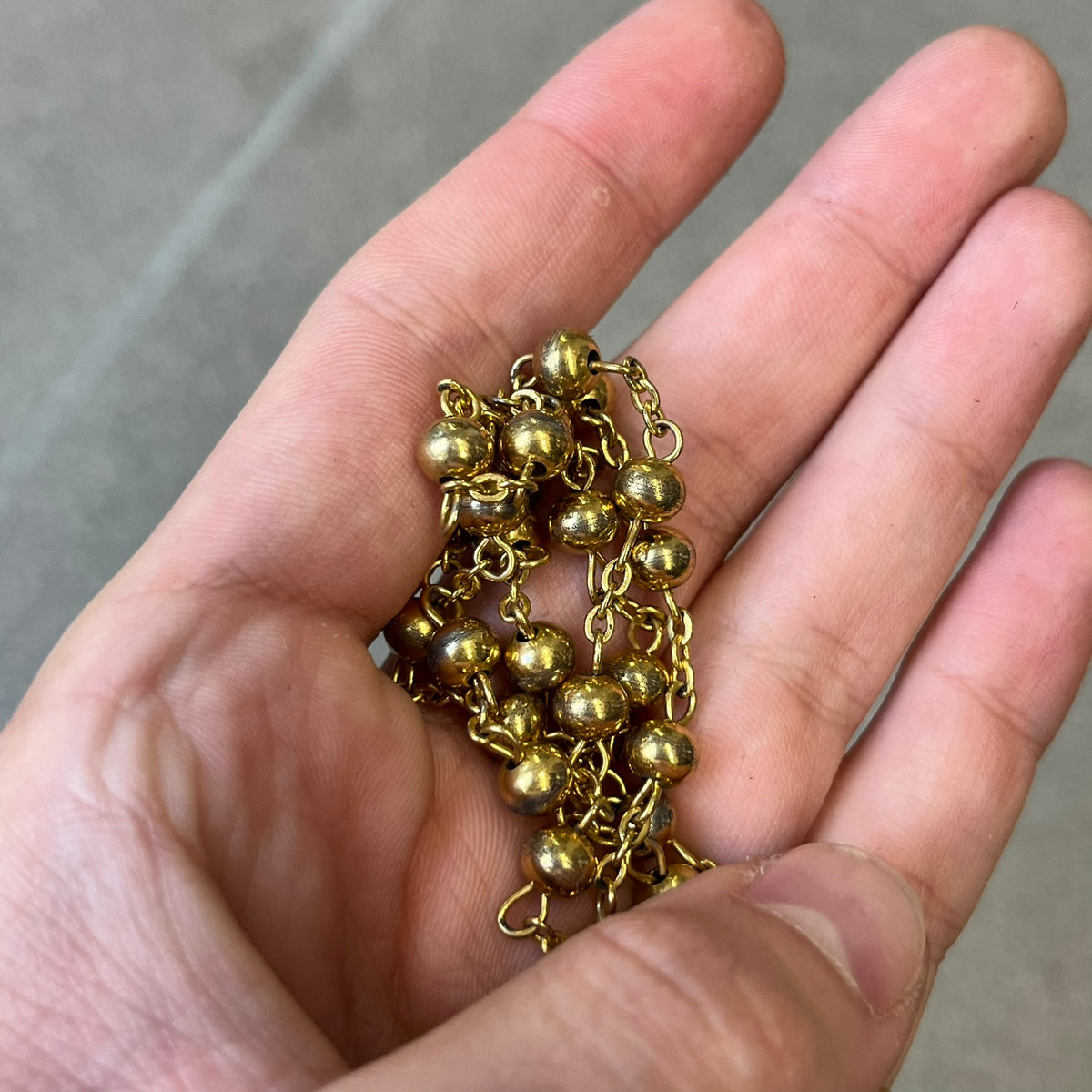 Dolce & Gabbana SS2003 Golden Cross Dog Tag Necklace features a curved-edge dog tag pendant with a cutout Latin cross in the center and engraved "Dolce & Gabbana" script text below it. It comes on a thin chain set with fixed beaded accents at regular intervals.