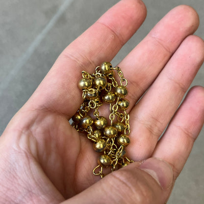 Dolce & Gabbana SS2003 Golden Cross Dog Tag Necklace features a curved-edge dog tag pendant with a cutout Latin cross in the center and engraved "Dolce & Gabbana" script text below it. It comes on a thin chain set with fixed beaded accents at regular intervals.