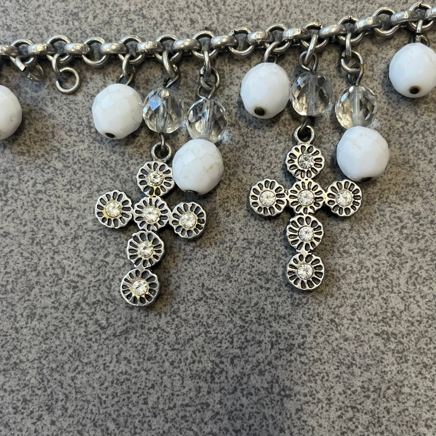 Dolce &amp; Gabbana Silver Charm Cross DJ0253 Bracelet features a silver-tone chain bracelet with white bead charms, three cross-shaped charms made from circular elements, and a D&amp;G logo charm. The bracelet has a silver-tone metal construction.&nbsp;