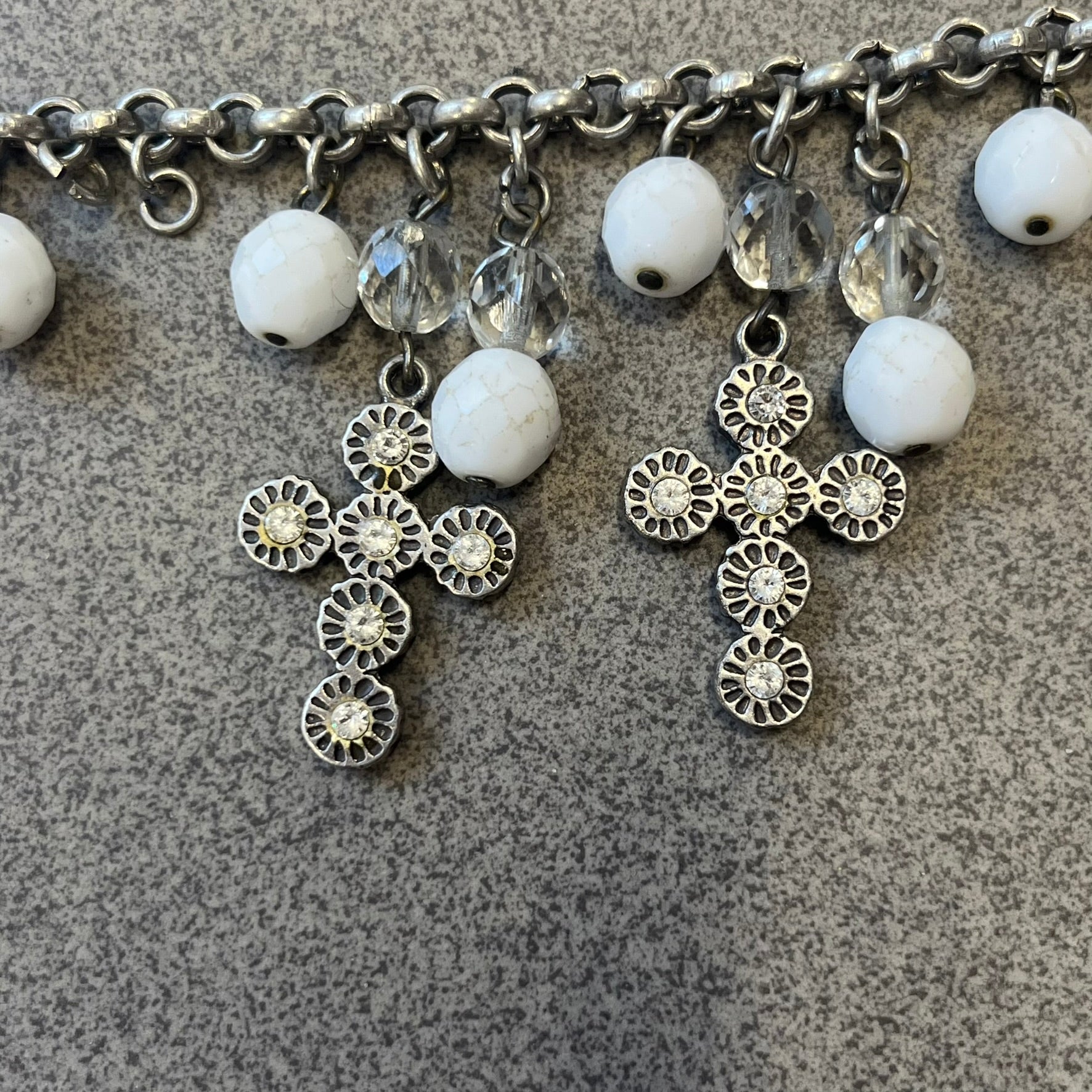 Dolce &amp; Gabbana Silver Charm Cross DJ0253 Bracelet features a silver-tone chain bracelet with white bead charms, three cross-shaped charms made from circular elements, and a D&amp;G logo charm. The bracelet has a silver-tone metal construction.&nbsp;