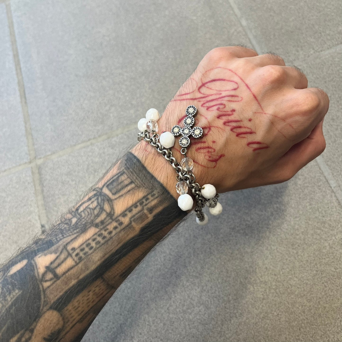 Dolce &amp; Gabbana Silver Charm Cross DJ0253 Bracelet features a silver-tone chain bracelet with white bead charms, three cross-shaped charms made from circular elements, and a D&amp;G logo charm. The bracelet has a silver-tone metal construction.&nbsp;