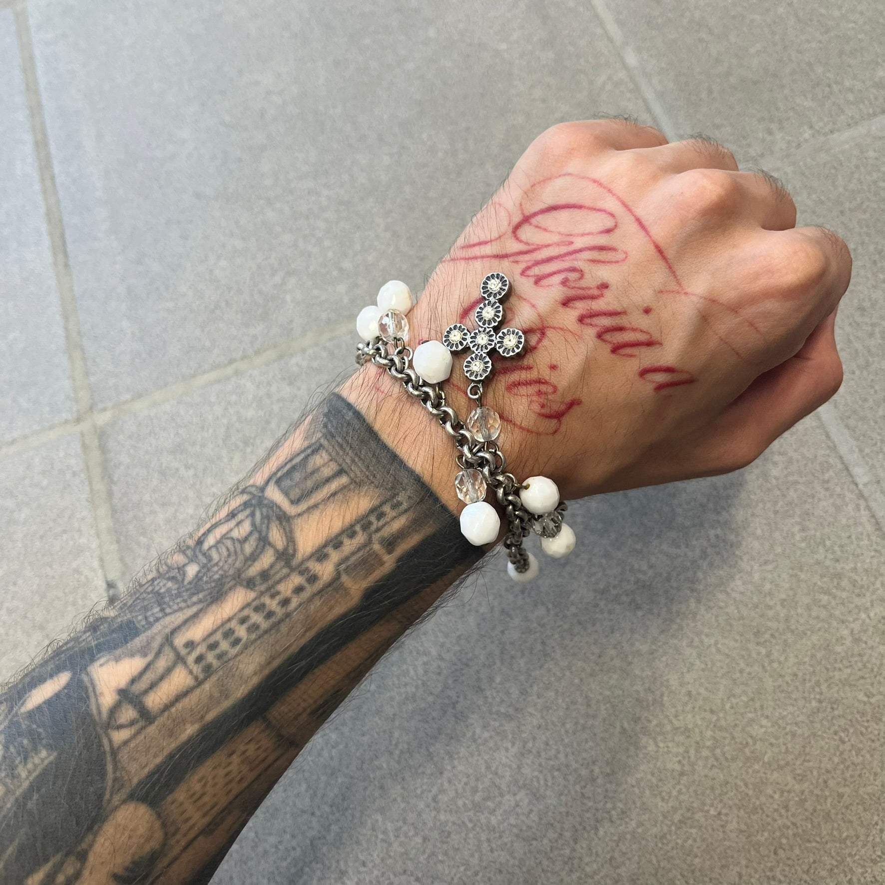 Dolce &amp; Gabbana Silver Charm Cross DJ0253 Bracelet features a silver-tone chain bracelet with white bead charms, three cross-shaped charms made from circular elements, and a D&amp;G logo charm. The bracelet has a silver-tone metal construction.&nbsp;