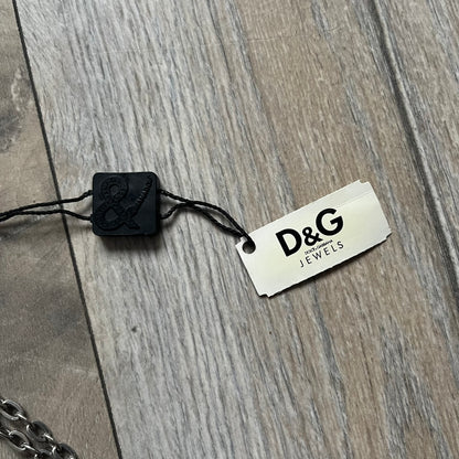 The Dolce & Gabbana Star Dog Tag Necklace (DJ0889) is a heavy stainless steel necklace featuring a thick, oversized dog tag pendant. The front of the pendant has a raised black star mounted on a silver-tone circular base, with open cutout sections between the star and the circle. A raised D&G logo is positioned at the lower front of the dog tag. The necklace is finished with a lobster clasp and has a solid, weighty construction throughout.