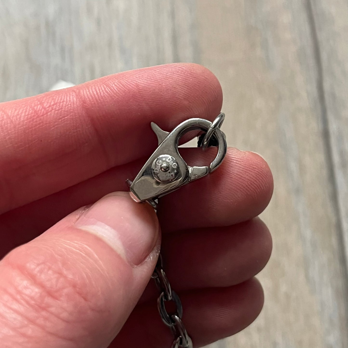 The Dolce & Gabbana Star Dog Tag Necklace (DJ0889) is a heavy stainless steel necklace featuring a thick, oversized dog tag pendant. The front of the pendant has a raised black star mounted on a silver-tone circular base, with open cutout sections between the star and the circle. A raised D&G logo is positioned at the lower front of the dog tag. The necklace is finished with a lobster clasp and has a solid, weighty construction throughout.