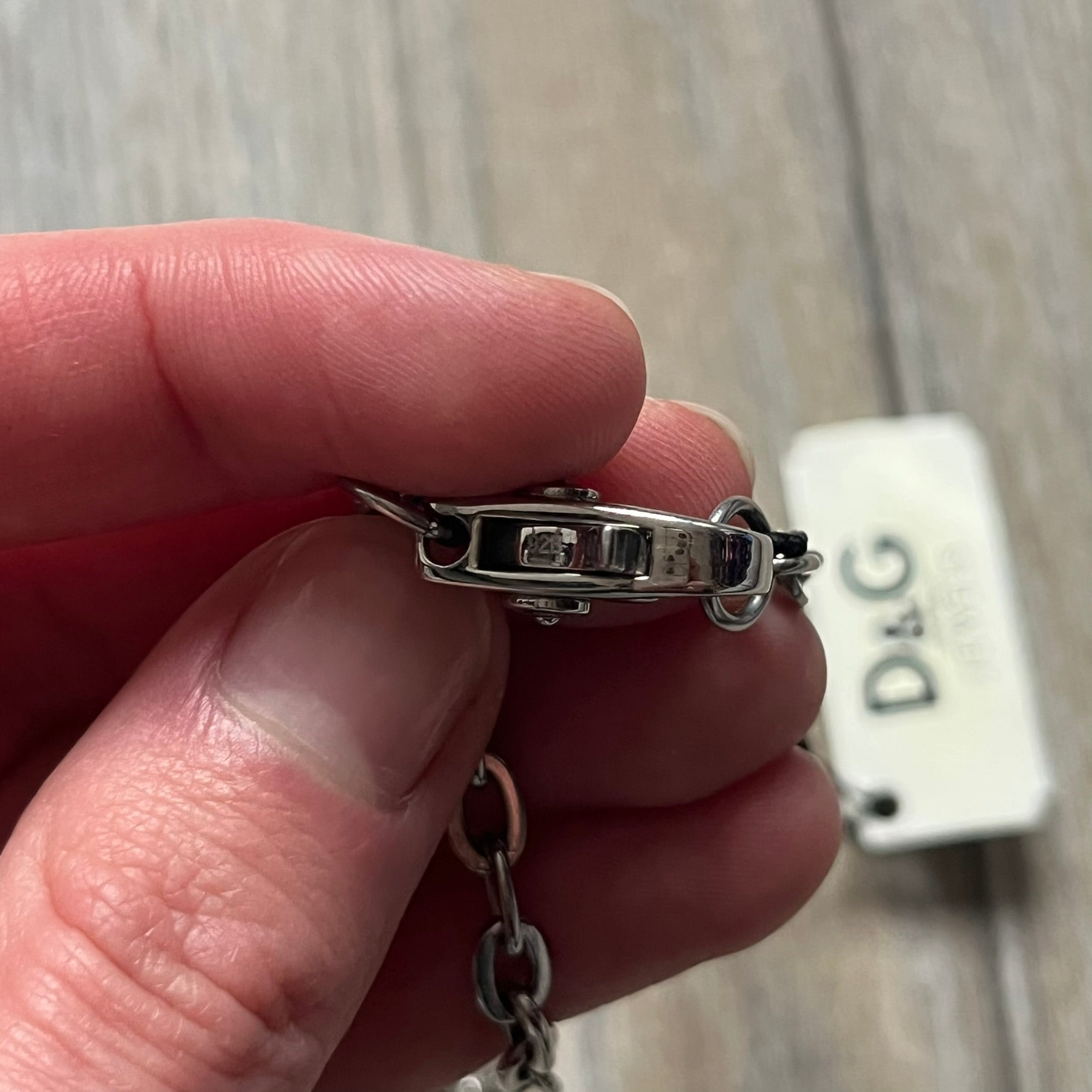 The Dolce & Gabbana Star Dog Tag Necklace (DJ0889) is a heavy stainless steel necklace featuring a thick, oversized dog tag pendant. The front of the pendant has a raised black star mounted on a silver-tone circular base, with open cutout sections between the star and the circle. A raised D&G logo is positioned at the lower front of the dog tag. The necklace is finished with a lobster clasp and has a solid, weighty construction throughout.