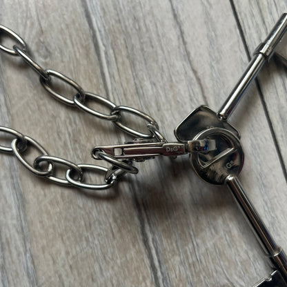 Dolce & Gabbana Two Keys Necklace is a stainless steel necklace featuring a paperclip chain design. At the center, it has a large lobster clasp holding two D&G logo-tagged keys, one with a circular top and the other with a square top. The clasp is engraved in multiple places, and the necklace comes with the original box and dust bag.