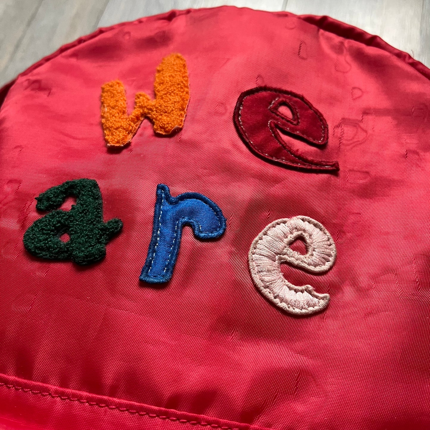 The Dolce & Gabbana "We Are D&G" Red Backpack is crafted from durable red nylon with metal hardware and features a graffiti-inspired "We Are D&G" logo embroidered on the front. It has a top zip closure, exterior zip pocket, padded back panel, and adjustable shoulder straps with canvas and faux leather details. The backpack also includes a top handle, rear identification label holder, and is made in Italy.