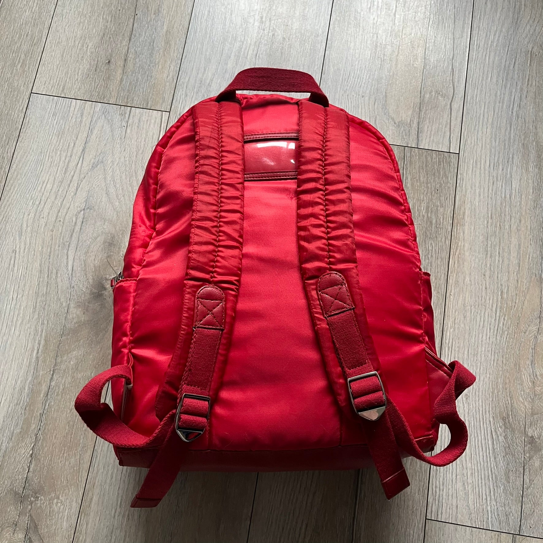 The Dolce & Gabbana "We Are D&G" Red Backpack is crafted from durable red nylon with metal hardware and features a graffiti-inspired "We Are D&G" logo embroidered on the front. It has a top zip closure, exterior zip pocket, padded back panel, and adjustable shoulder straps with canvas and faux leather details. The backpack also includes a top handle, rear identification label holder, and is made in Italy.