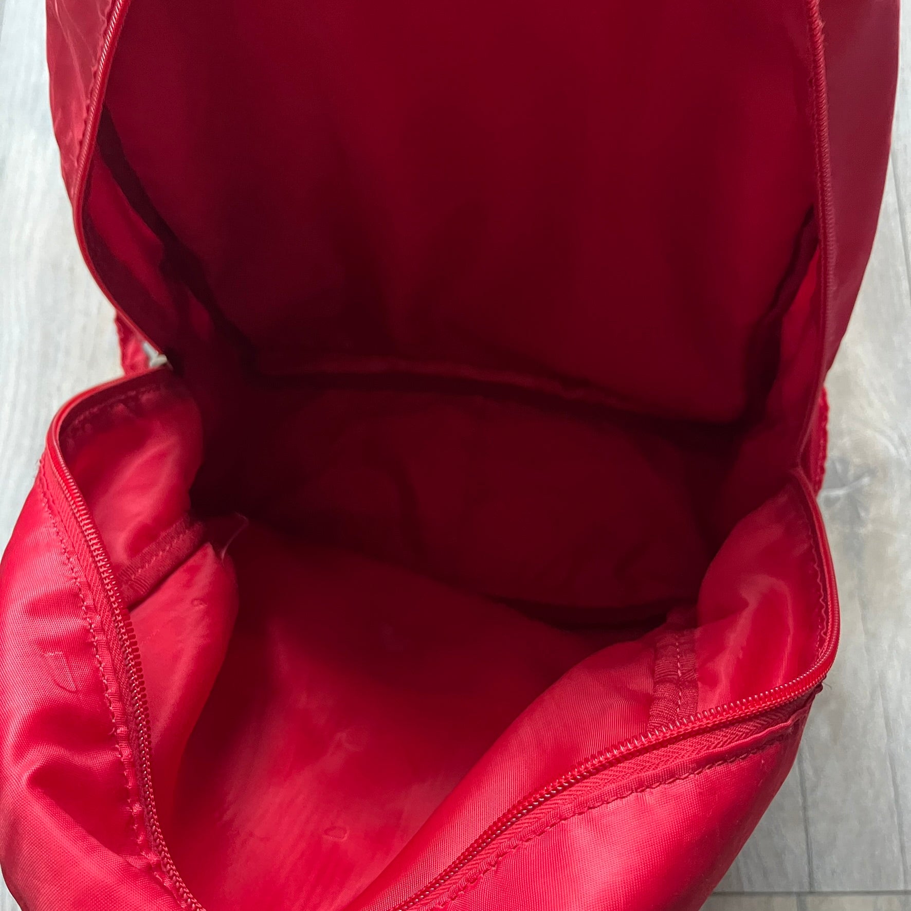 The Dolce & Gabbana "We Are D&G" Red Backpack is crafted from durable red nylon with metal hardware and features a graffiti-inspired "We Are D&G" logo embroidered on the front. It has a top zip closure, exterior zip pocket, padded back panel, and adjustable shoulder straps with canvas and faux leather details. The backpack also includes a top handle, rear identification label holder, and is made in Italy.