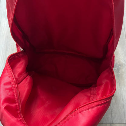 The Dolce & Gabbana "We Are D&G" Red Backpack is crafted from durable red nylon with metal hardware and features a graffiti-inspired "We Are D&G" logo embroidered on the front. It has a top zip closure, exterior zip pocket, padded back panel, and adjustable shoulder straps with canvas and faux leather details. The backpack also includes a top handle, rear identification label holder, and is made in Italy.