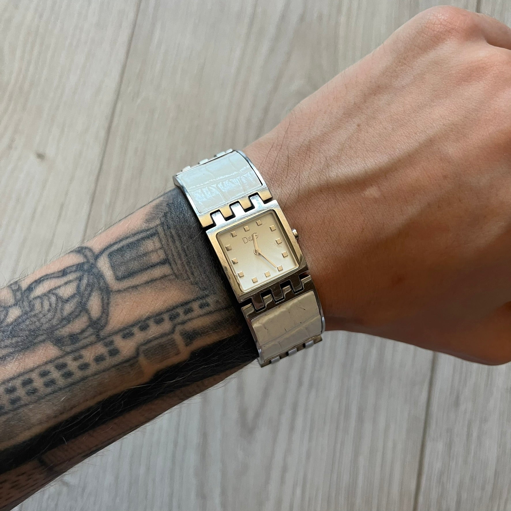 Dolce &amp; Gabbana white analog watch with a silver bracelet featuring white leather-like panels. The case seamlessly aligns with the width of the bracelet for a sleek, integrated look. A refined statement piece blending luxury design with modern elegance.