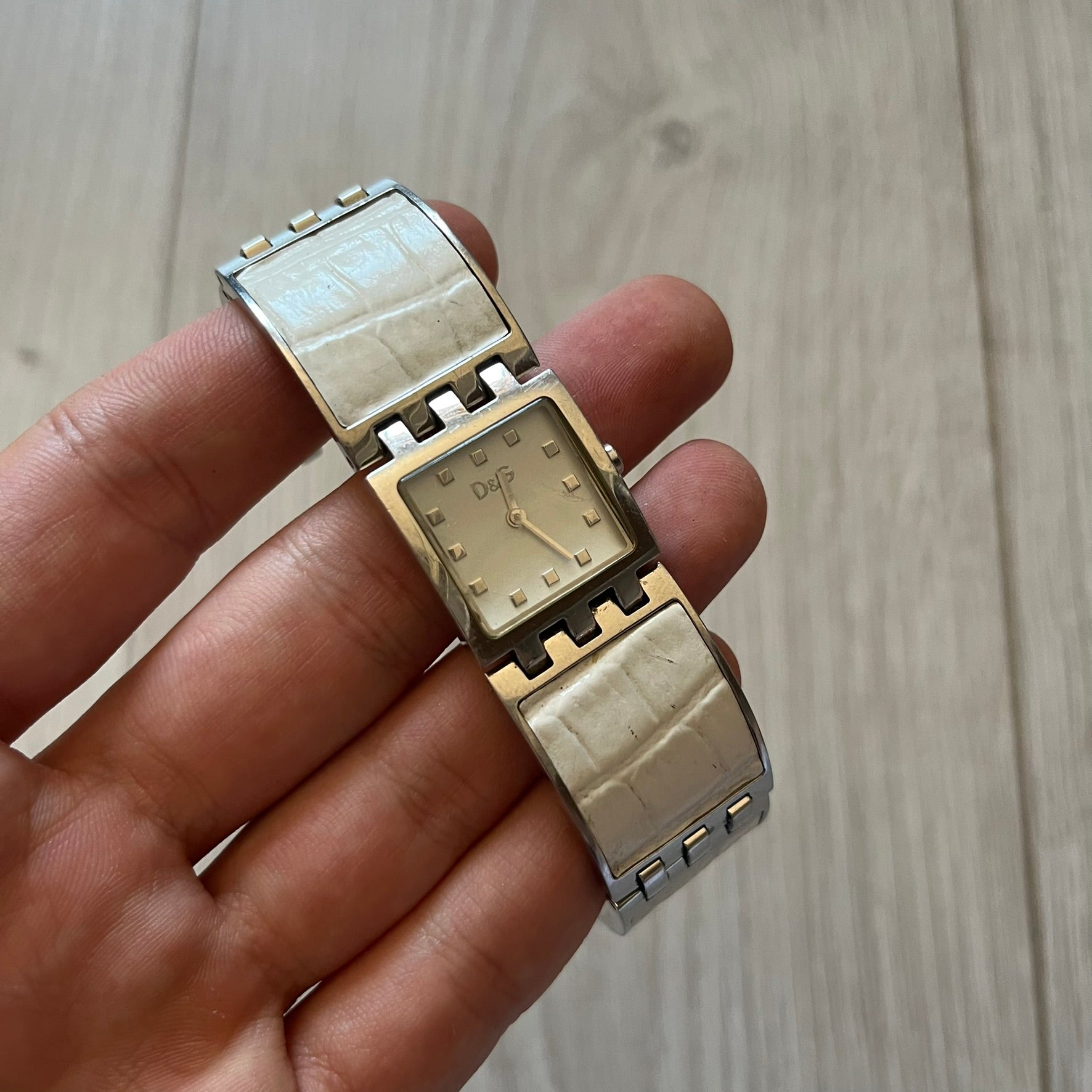 Dolce &amp; Gabbana white analog watch with a silver bracelet featuring white leather-like panels. The case seamlessly aligns with the width of the bracelet for a sleek, integrated look. A refined statement piece blending luxury design with modern elegance.