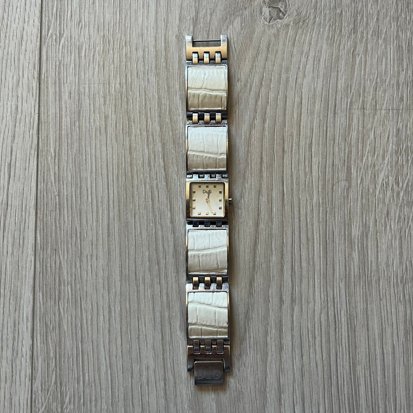 Dolce &amp; Gabbana white analog watch with a silver bracelet featuring white leather-like panels. The case seamlessly aligns with the width of the bracelet for a sleek, integrated look. A refined statement piece blending luxury design with modern elegance.