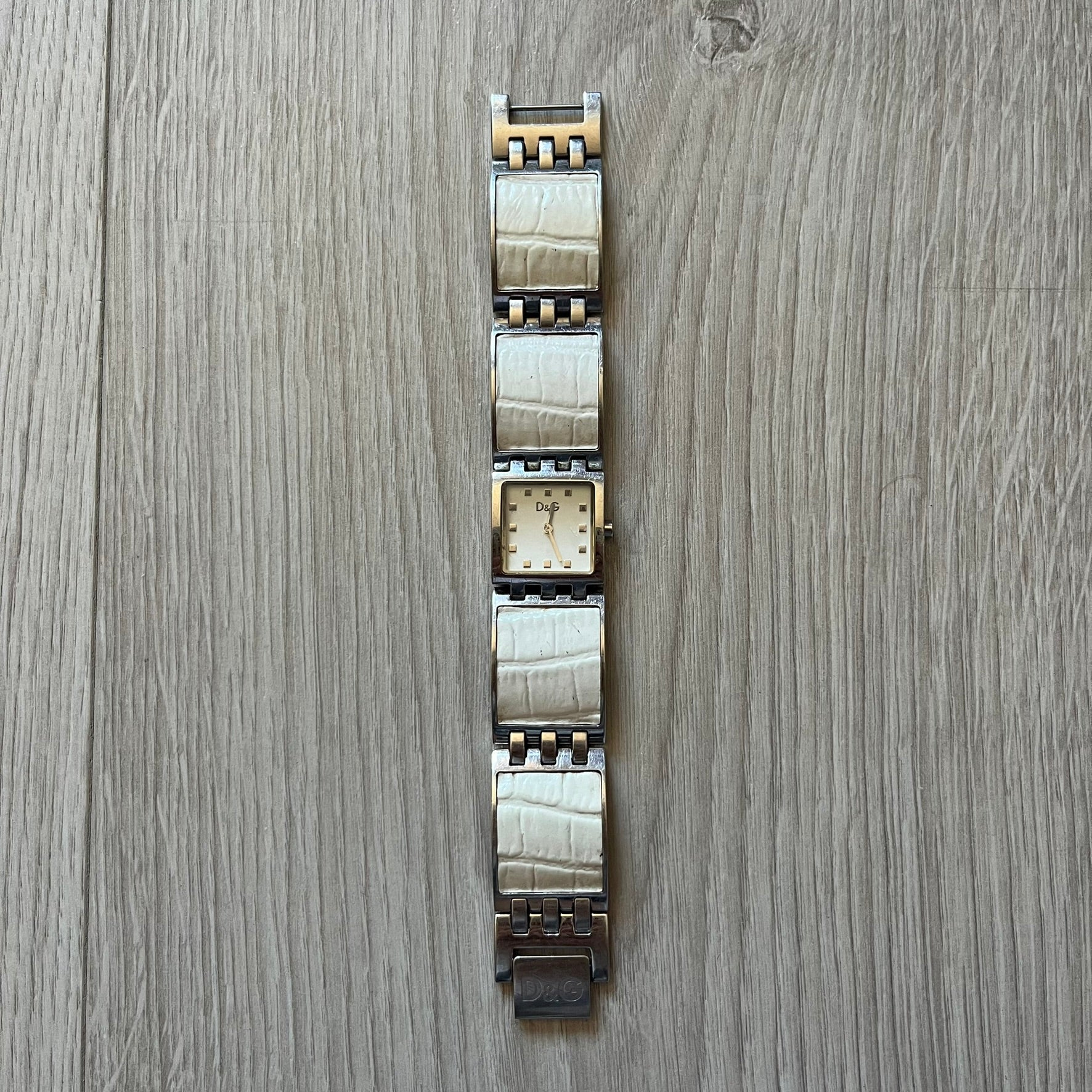 Dolce &amp; Gabbana white analog watch with a silver bracelet featuring white leather-like panels. The case seamlessly aligns with the width of the bracelet for a sleek, integrated look. A refined statement piece blending luxury design with modern elegance.